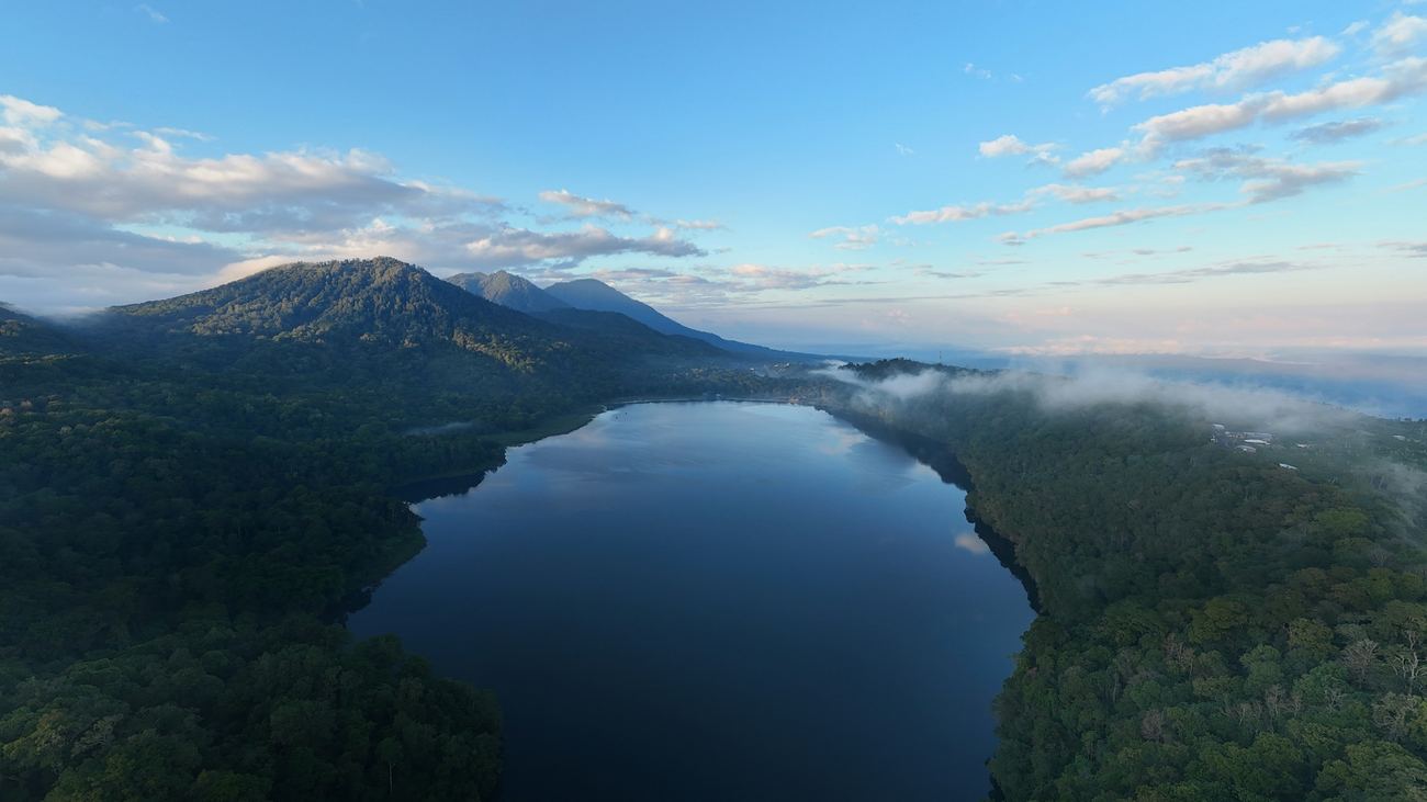 A crater lake in the forested highlands of North Bali, cloud lifting off the trees.